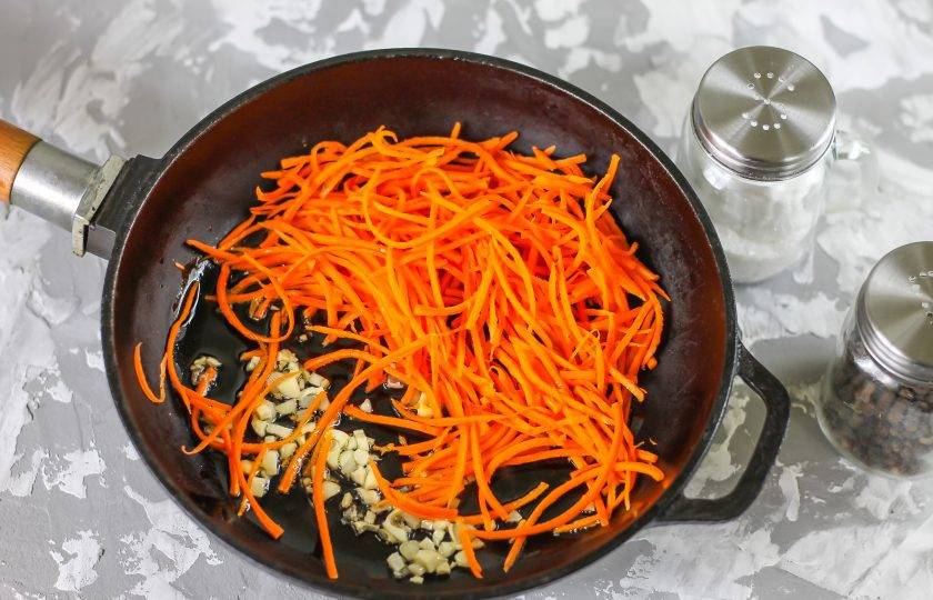 1. Этап. Салат из селедки с морковью: Очистите от шелухи чесночные зубчики, измельчите или спрессуйте. Раскалите сковороду с растительным маслом, высыпьте в нее чесночную нарезку и морковную. Томите около 1-2 минут, присыпав молотым кориандром. Затем выложите на тарелку и остудите.