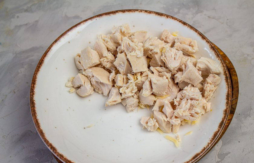 1. Этап. Салат Снежная горка: Отварное куриное филе нарежьте небольшим кубиком, выложите в тарелку.
