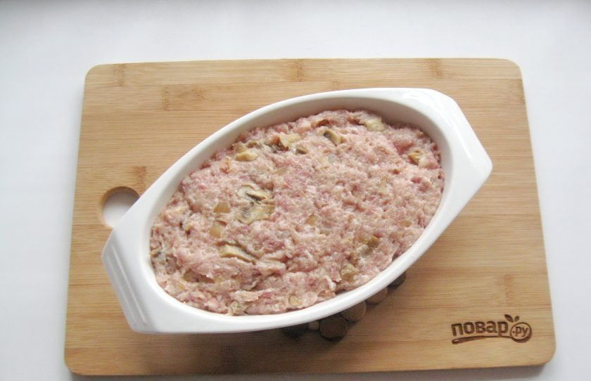 1. Этап. Мясной хлеб с грибами: Форму для запекания мясного хлеба смажьте маслом и выложите приготовленный фарш.