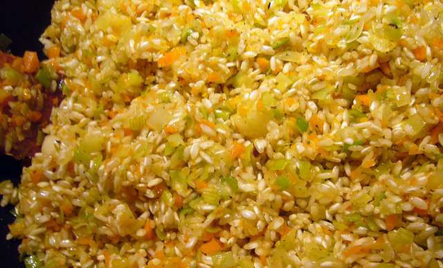 1. Этап. Ризотто с овощами и грибами: Засыпьте на сковороду рис. Перемешивая продолжаем готовить, пока все масло не впитается в рис. Далее, вливаем вино и ждем пока оно испарится.