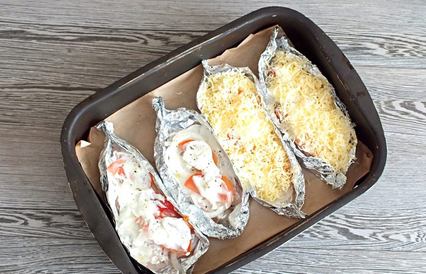 1. Этап. Пикша в духовке под сыром: Помидоры смажьте опять сметаной, если необходимо еще раз посолите, посыпьте перцем. Разложите натертый на мелкой терке сыр.