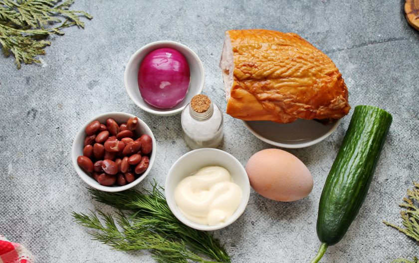 1. Этап. Салат из копченой куриной грудки с фасолью и огурцом: Подготовьте все необходимые ингредиенты для приготовления салата с копченой куриной грудкой с фасолью и огурцами. Красный лук почистите, лук, огурец и зелень вымойте и обсушите. Консервированную фасоль откиньте на сито и дайте жидкости полностью стечь.