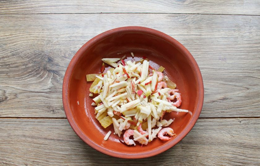 1. Этап. Салат с креветками, яблоком и ананасом: Яблоко вымойте, разрежьте пополам, удалите сердцевину и порежьте соломкой. Выложите яблоко в миску с креветками и ананасом.