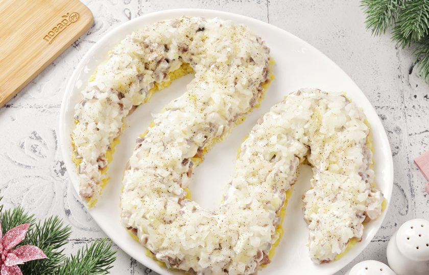 1. Этап. Селедка под шубой на год Змеи 2025: Лук нарежьте кубиками и залейте на пару минут крутым кипятком. Этот способ уберет из лука горечь. Затем слегка отожмите лук и выложите следующим слоем. Посолите, поперчите по желанию и смажьте майонезом.