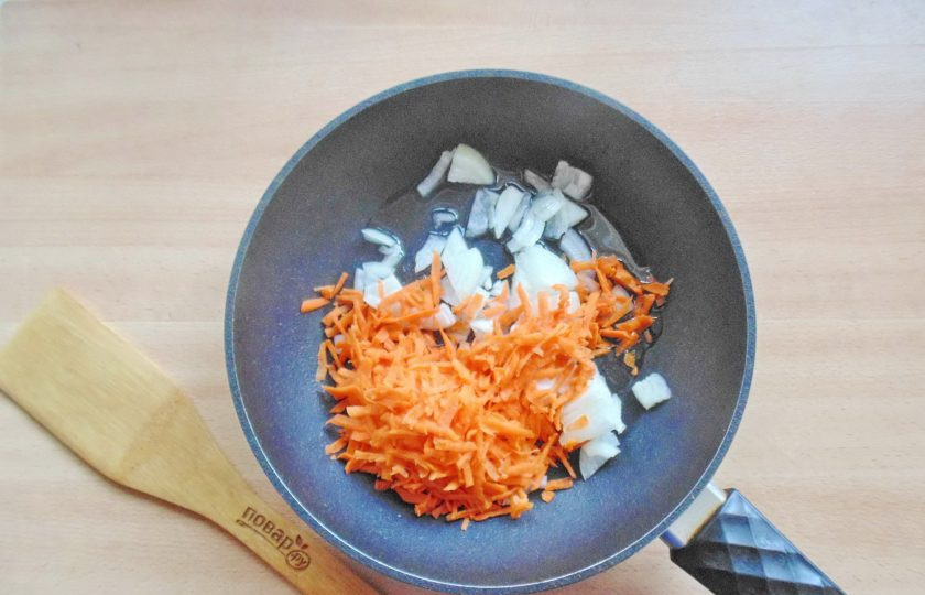 1. Этап. Хек с кабачками в духовке: Морковь и лук очистите, ополосните. Морковь натрите на тёрке, лук нарежьте мелко. Выложите в сковороду и добавьте подсолнечное масло.