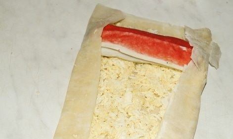 1. Этап. Рулетики из теста фило с крабово-сырной начинкой: 5. На край положите крабовый рулетик и аккуратно заверните.