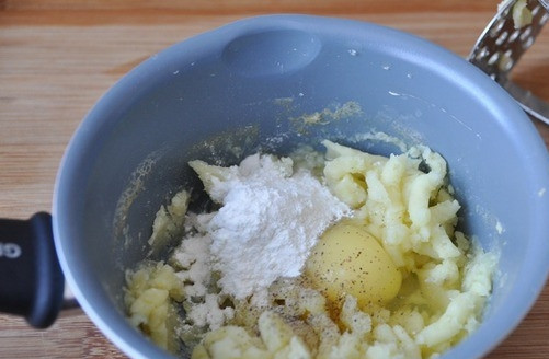 1. Этап. Картофельные гнезда с фаршем: Отваренный картофель остудите, слейте с него воду. Переложите его в миску. Потолките его толкушкой. Положите к пюре сырое яйцо, специи, муку и соль. Тщательно все перемешайте, чтобы получилось своеобразное картофельное тесто.