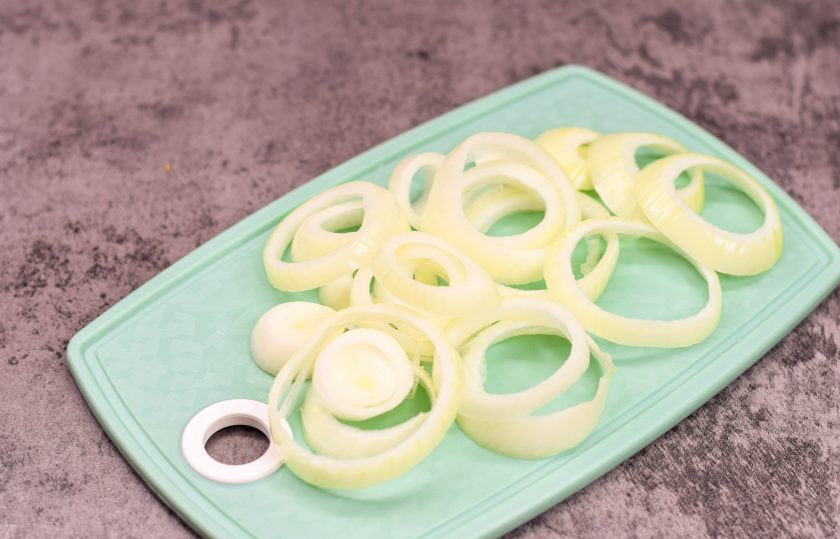 1. Этап. Обжаренные луковые кольца: Очистите репчатый лук и сполосните, после просушите. Нарежьте лук кольцами, после чего разберите его на отдельные колечки.