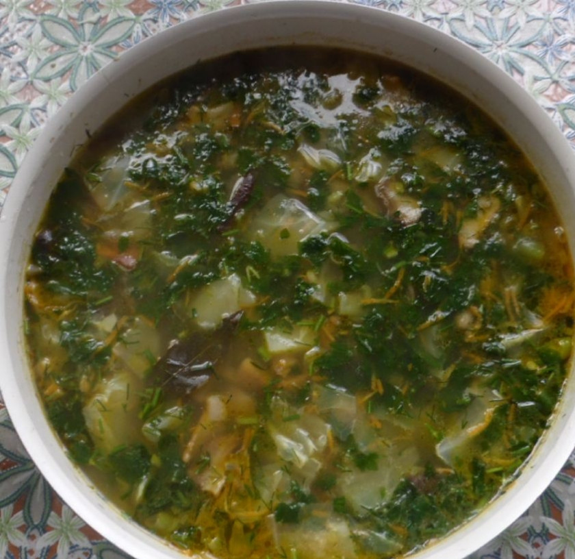 1. Этап. Грибной суп с капустой: Ножом измельчаем зелень и чеснок, добавляем в суп. Варим 5 минут, помешивая.