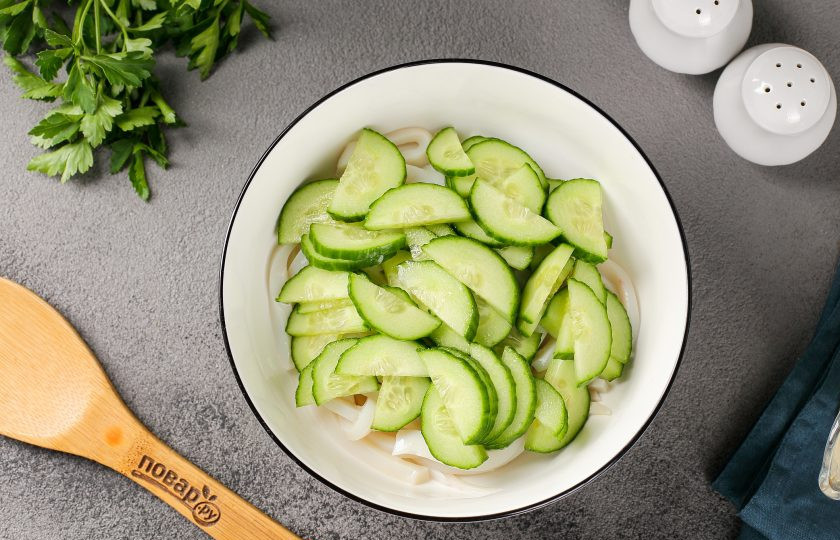 1. Этап. Кальмаровый салат с огурцом: Добавьте нарезанные полукругом или соломкой огурцы.