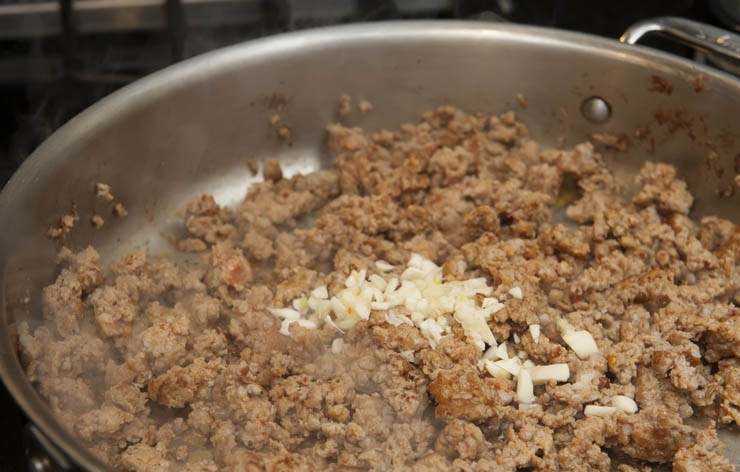 1. Этап. Паста с мясным фаршем: Макароны ставим вариться. Разогреваем оливковое масло на сковороде, добавляем туда измельченные колбаски и чеснок. Обжариваем пару минут, после чего добавляем 2 стакана бульона (или же 1 стакан белого сухое вина и 1 стакан куриного бульона)