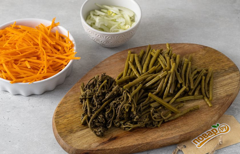 1. Этап. Салат из соленого папоротника по-корейски: Морковь помойте и очистите. Натрите на терке для моркови по-корейски. Репчатый лук нарежьте полукольцами. Папоротник нарежьте на ломтики 3-5 см.