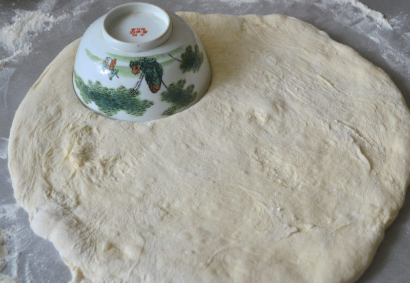 1. Этап. Панцеротти: Присыпьте стол мукой, так как тесто достаточно липкое. Раскатайте его в пласт. Сделайте лепешки для пирогов, можно использовать подручные средства в качестве шаблона, а можно просто разделить на кусочки и раскатывать их.