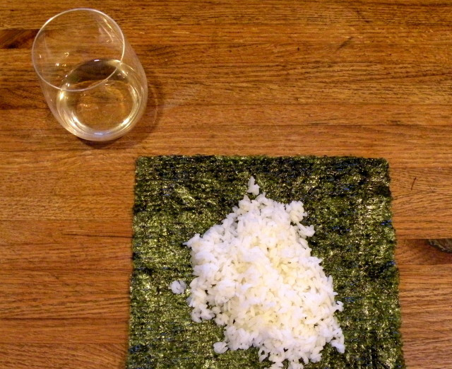 1. Этап. Постные роллы: 1. Отварите рис для суши согласно указаниям на его упаковке. Остудите его. Приготовьте стакан или миску с водой. Выложите пару ложек риса на лист нори.