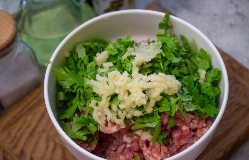 1. Этап. Баклажаны с фаршем по-китайски: В фарш добавьте чеснок, пропущенный через пресс и мелко нарезанную зелень петрушки.