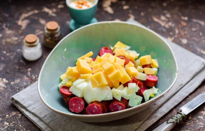 1. Этап. Салат Ежик с колбасой: Твердый сыр нарежьте небольшими кубиками и добавьте в салат.