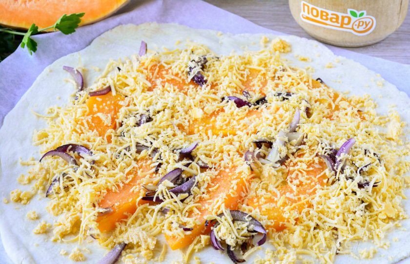 1. Этап. Пирог с тыквой открытый: В центр выложите всю начинку, оставляя края свободными. Распределите обжаренную тыкву, лук, а сверху присыпьте пирог натертым сыром.