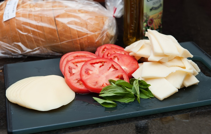 1. Этап. Горячий бутерброд на сковороде: 1. Приготовьте ингредиенты для горячих бутербродов. Помидоры промойте, вырежьте плодоножку и нарежьте кружочками. Моцареллу также нарежьте пластинками. Базилик промойте и просушите.