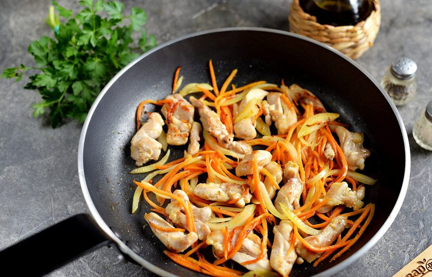 1. Этап. Лапша по-корейски с курицей: Добавьте в сковороду тонко нашинкованную морковь и нарезанный полукольцами репчатый лук. Обжарьте минуты полторы до мягкости овощей.