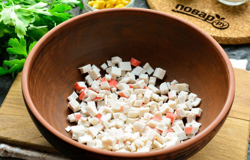 1. Этап. Салат Неженка с крабовыми палочками: Охлажденные крабовые палочки почистите от упаковки-пленки, нарежьте продукт средними кубиками.