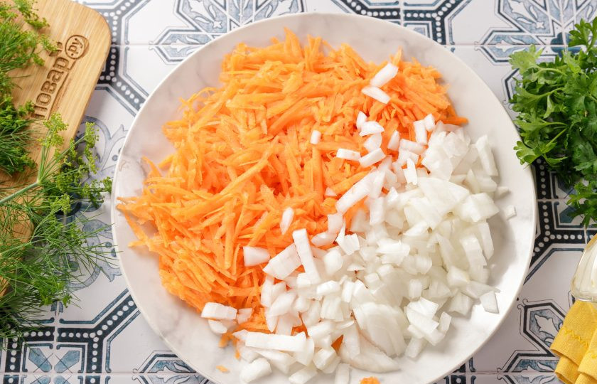 1. Этап. Салат с фасолью, морковью и колбасой: Лук нарежьте кубиками, а морковь натрите на крупной тёрке.