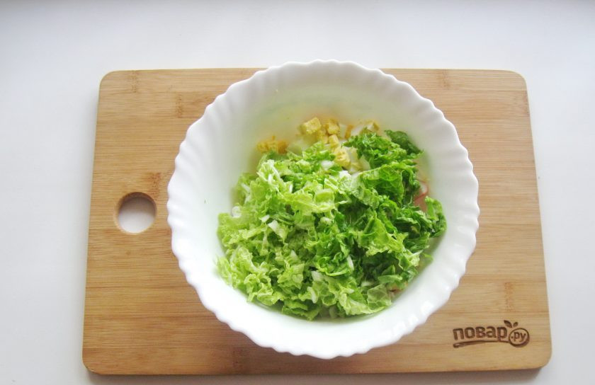 1. Этап. Салат с дайконом и крабовыми палочками: Пекинскую капусту нарежьте тонко. Добавьте в салатник.