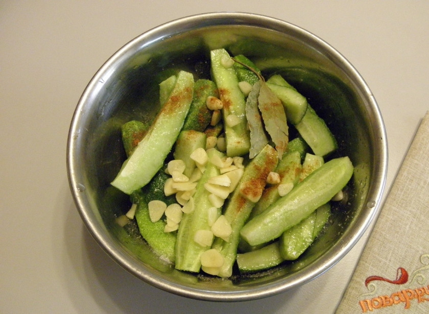 1. Этап. Маринованные огурцы в собственном соку: Добавьте к огурцам соль, сахар, уксус, масло растительное, рубленый чеснок, лавровый лист и перец чили молотый. Перемешайте и оставьте стекать соком на 3-4 часа.