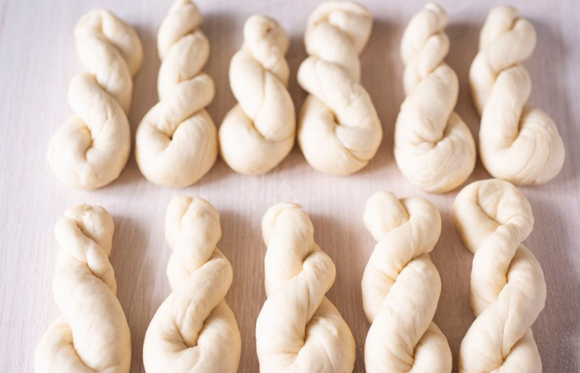 1. Этап. Корейские пончики: Каждую часть теста сначала раскатайте в жгутик, при этом один конец крутите в одну сторону, а другой конец крутите в противоположную сторону, а затем свободные концы скрепите и сформируйте заготовки пончиков, как на фото. Когда подготовите все заготовки пончиков, то дайте им полежать на столе 15 минут (накройте их кухонным полотенцем на это время).