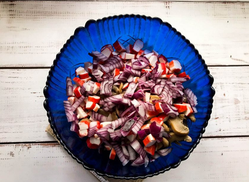 1. Этап. Салат с фасолью, грибами и крабовыми палочками: Лук очистите от шелухи, мелко нарежьте и добавьте к остальным ингредиентам.