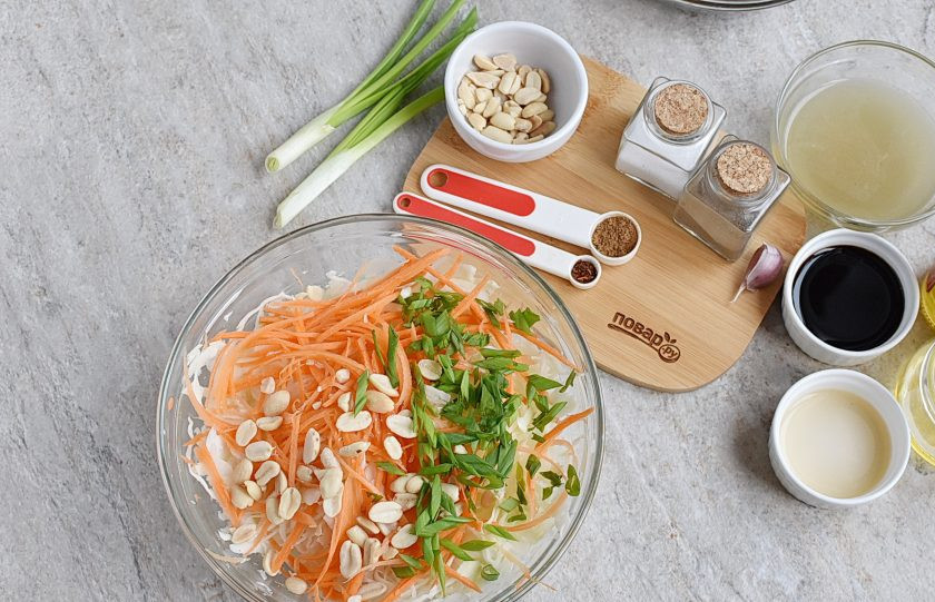 1. Этап. Китайский салат из капусты: Добавьте шинкованный зеленый лук и половину арахиса.