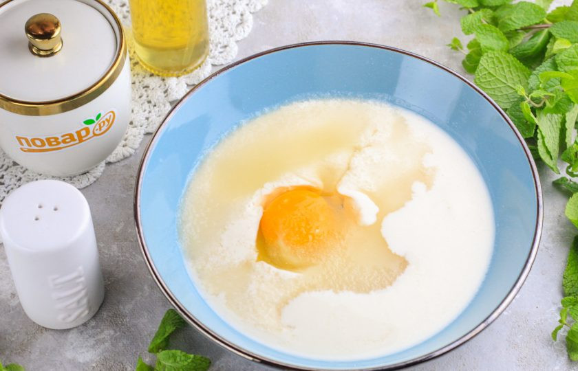 1. Этап. Шоколадные оладьи на кефире: Влейте кефир в глубокую емкость и вбейте туда же куриное яйцо. Всыпьте сахар и соль. По желанию можно добавить немного ванильного сахара. Взбейте все венчиком.