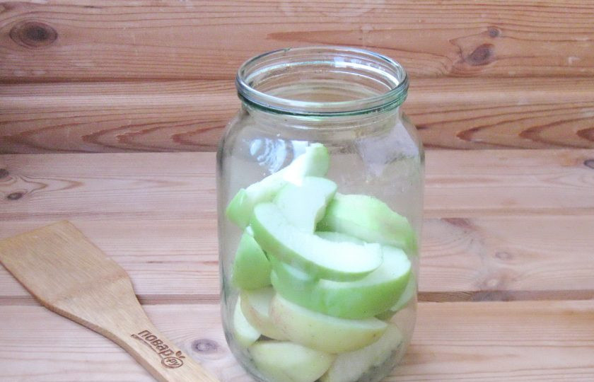 1. Этап. Компот из яблок с лимонной кислотой на зиму: Яблоки вымойте, удалите плодоножку и семенную коробочку. Нарежьте дольками. Выложите в стерилизованную банку.