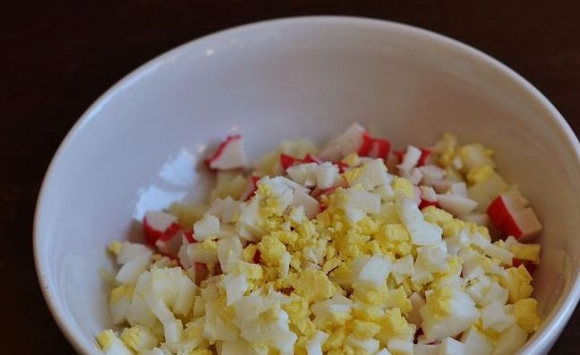 1. Этап. Салат с крабовыми палочками, яйцом и майонезом: Яйца положите в кастрюлю, залейте холодной водой и поставьте на плиту. Варите яйца десять минут, затем остудите под струей холодной воды. Очистите их от скорлупы и нарежьте. Отправьте яйца к остальным ингредиентам.