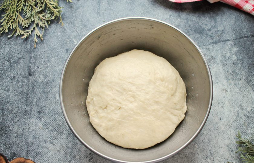 1. Этап. Чесночные булочки в духовке из дрожжевого теста: Муку смешайте с разрыхлителем и просейте. Частями добавляйте муку в теплую массу и замесите мягкое, не липкое тесто. Вымешивайте тесто в течение 8-10 минут. Сформируйте тесто в шар и положите обратно в миску.