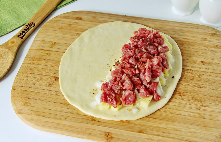 1. Этап. Корниш пасти: Разделите тесто на 4-6 частей. Каждую раскатайте поочередно в форме круга, диаметром 15-20 см. Ближе к одному краю выложите в следующей последовательности: картофель, лук и мясо. Каждый слой необходимо посолить, поперчить и посыпать специями по вкусу.