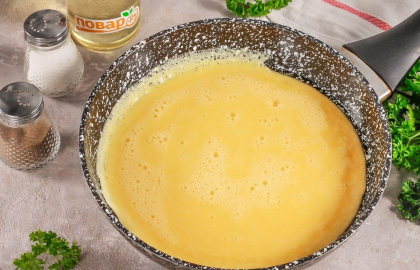 1. Этап. Пышный омлет на сковороде без молока: Прогрейте сковороду с растительным маслом на плите и смажьте даже бока емкости, чтобы омлет к ним не прилип. Влейте яичную массу только в прогретое масло и сразу же накройте крышкой. Убавьте нагрев до минимума.