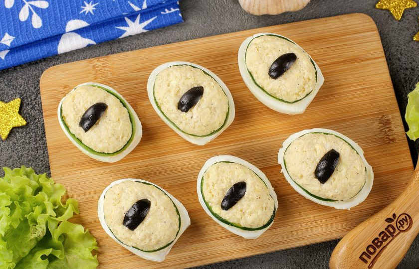 1. Этап. Фаршированные яйца Глаз дракона: Маслину нарежьте на полоски и выложите по центру яйца. Получатся фаршированные яйца, внешне напоминающие драконий глаз.