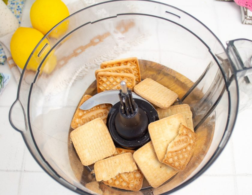 1. Этап. Лимонный чизкейк без выпечки: Приготовьте основу. В чашу блендера выложите песочное печенье и измельчите его в мелкую крошку.