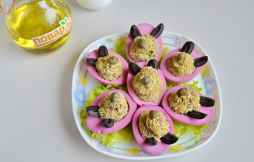 1. Этап. Пасхальные мордашки: 9. На тарелочку положите несколько листочков салата, разместите половинки яиц. Из оливок и каперсов сделайте мордашки.