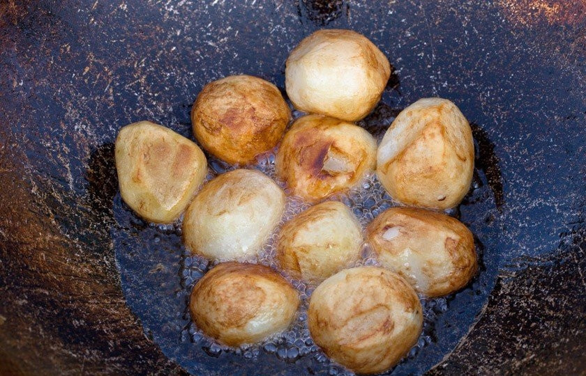 1. Этап. Картофель, тушенный со свининой и овощами: Это блюдо я готовлю в казане. Очистите картофель от кожуры, вымойте его под проточной водой. Налейте в казан масло, выложите в него цельный картофель и жарьте до готовности. После того как он будет готов, выложите его из казана.