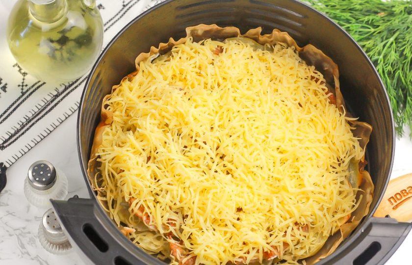 1. Этап. Мясо по-французски в аэрогриле: Пока свинина готовится, натрите твердый сыр любого сорта на терке с мелкими ячейками и выложите поверх свинины.