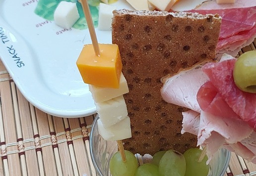1. Этап. Фуршетный стаканчик Фруктово-сырно-мясной: Собираем стаканчик. К задней стенке прислоняем хлебец и сыпем на дно виноград. Шпажки втыкаем в виноградины.