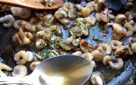 1. Этап. Креветки с грибами: Добавляем шампиньоны, обжариваем их до румяной корочки. Откладываем в сковороду креветки, зелень и перец. Вливаем соевый соус. Далее — грецкое и кунжутное масло.