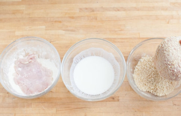 1. Этап. Салат с курицей: Разложите муку и сухари в отдельные емкости. В еще одну емкость налейте молоко. Обваляйте куриное филе в муке, после чего окуните в молоко и присыпьте панировочными сухарями.