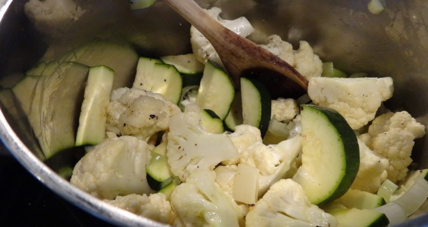 1. Этап. Суп с кабачками: 2. В кастрюлю налейте несколько столовых ложек оливкового масла, выложите кабачки, цветную капусту, измельченный чеснок, нарезанную кубиками картошку, оба вида лука. Посолите и поперчите, готовьте, помешивая 5-7 минут.