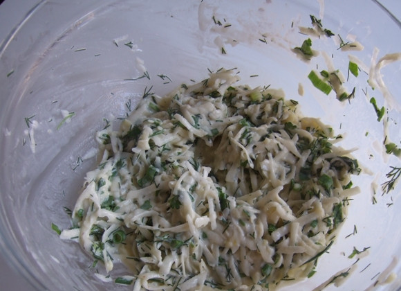 1. Этап. Мясо в сливках в духовке: Выкладываем в миску натертый картофель, измельченную зелень. Добавляем яйцо, сметану, измельченный чеснок, муку, пару щепоток соли и все хорошо перемешиваем.