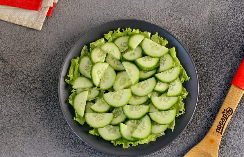 1. Этап. Диетический салат с консервированным тунцом: Сначала выложите листья салата. Перед этим листья предварительно промойте, обсушите и нарвите руками. Сверху распределите нарезанный огурец.