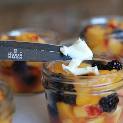 1. Этап. Десерт из персиков и ежевики: В каждую баночку кладем по кусочку сливочного масла.