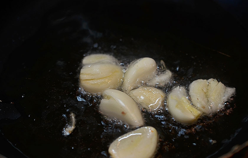 1. Этап. Паэлья с цыпленком и чорризо: 2. Зубчики чеснока раздавите ножом и обжарьте с добавлением масла.