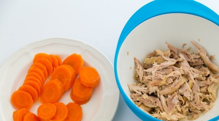 1. Этап. Холодец с курицей: 5. Достаньте овощи из бульона, выбросьте сельдерей, лавровый лист и лук, а морковь нарежьте тонкими кольцами. Свиные ноги уберите в сторону, а курицу измельчите. Процедите бульон через мелкое сито и марлю 3-4 раза, чтобы он был прозрачный.